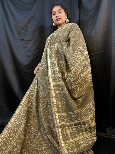Woman wearing a traditional gold and black patterned saree against a black background