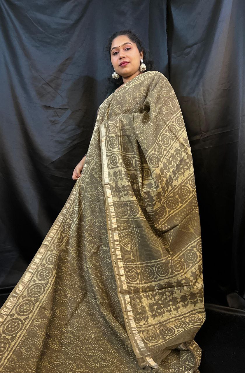Woman wearing a traditional gold and black patterned saree against a black background