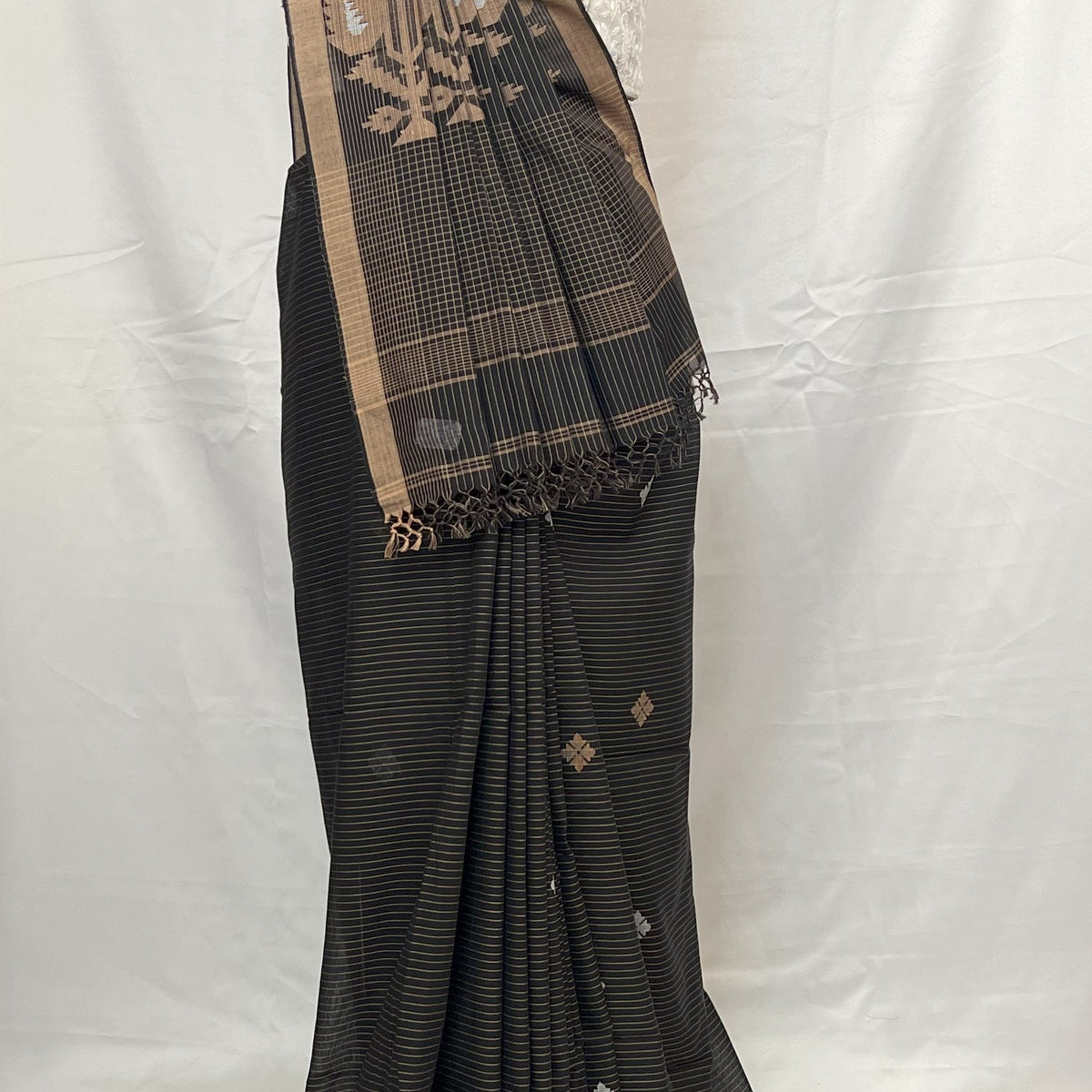 Black saree with gold border on a mannequin against a white background