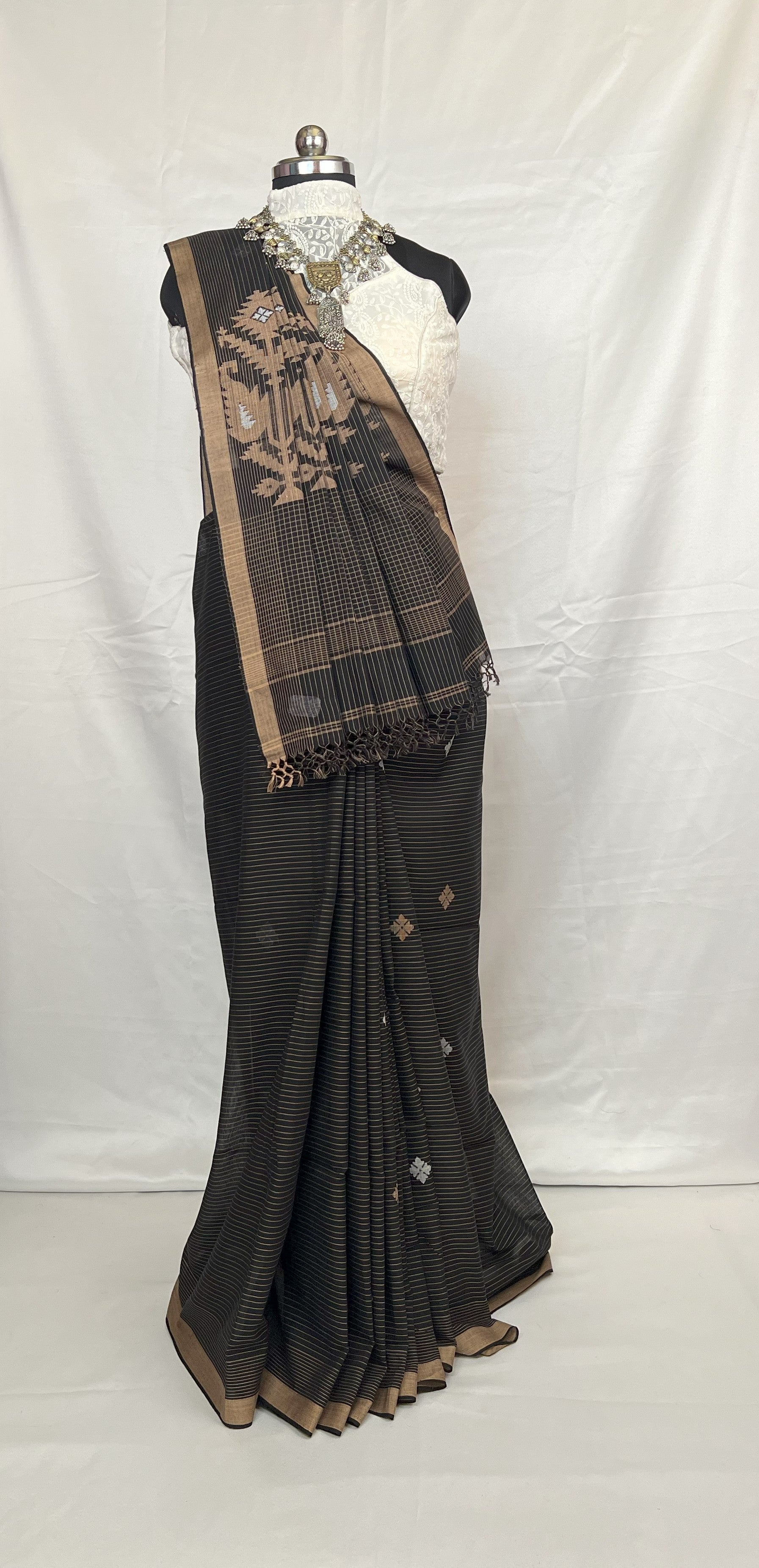 Black saree with gold border on a mannequin against a white background
