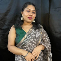 Woman wearing a green top and patterned saree against a black background
