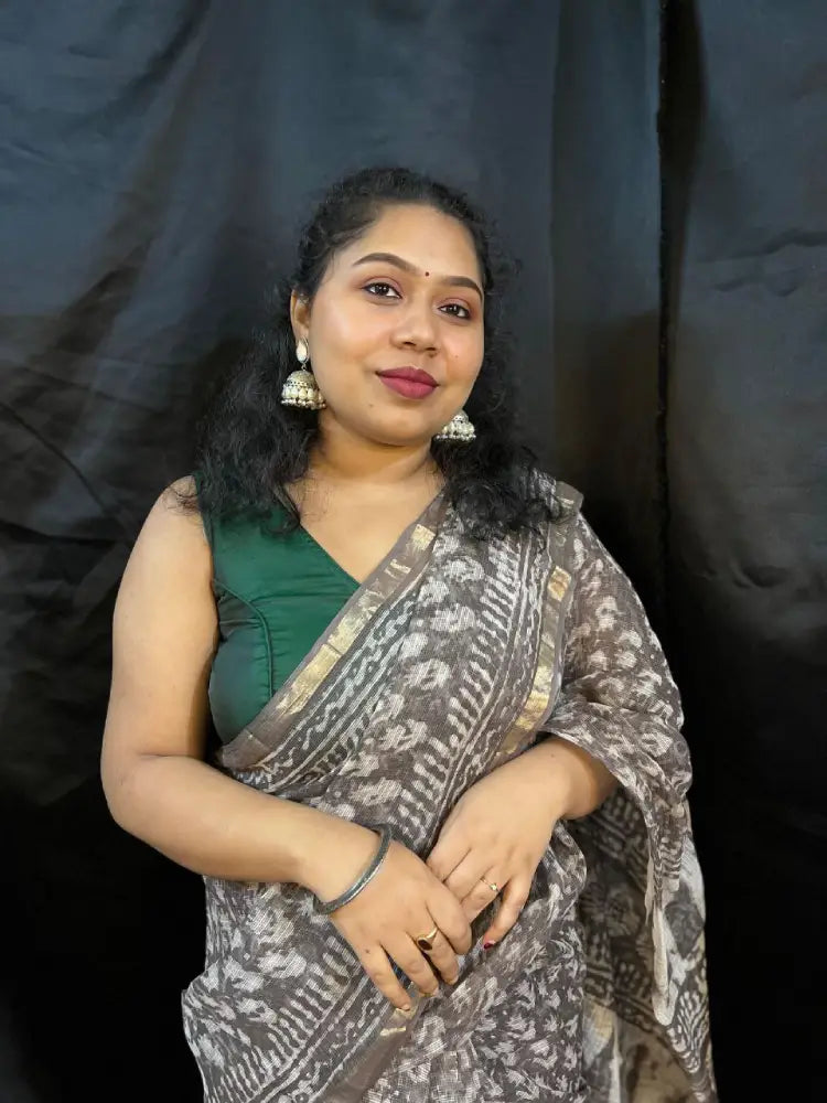 Woman wearing a green top and patterned saree against a black background