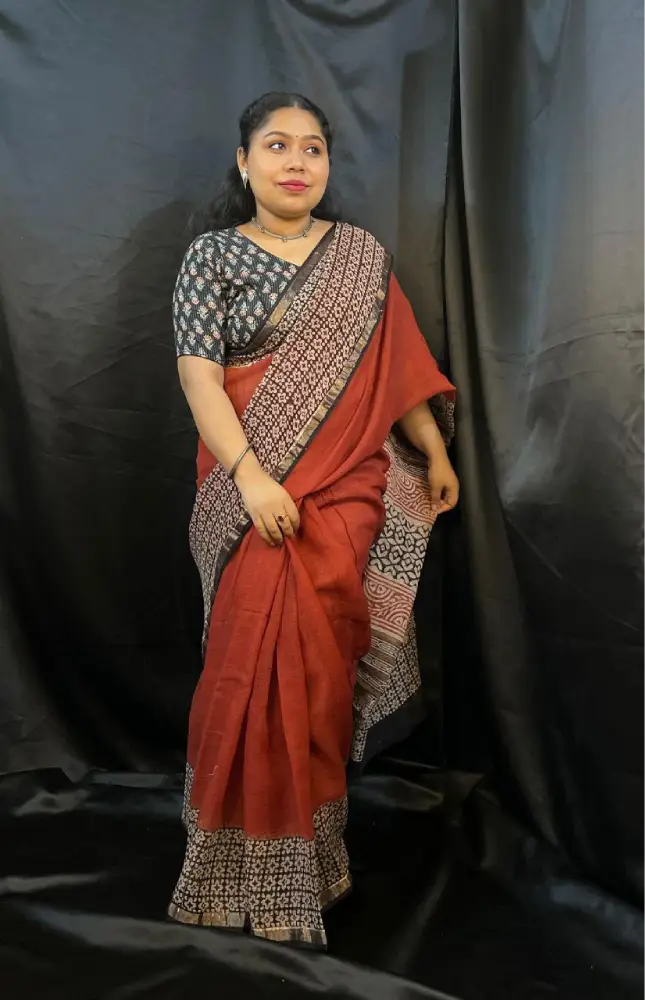 Woman wearing a red saree with a black and white blouse against a black background