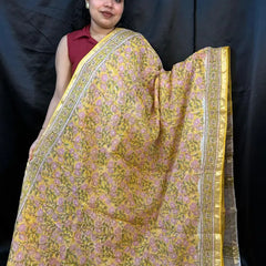 Woman wearing a yellow saree with a floral pattern against a black background