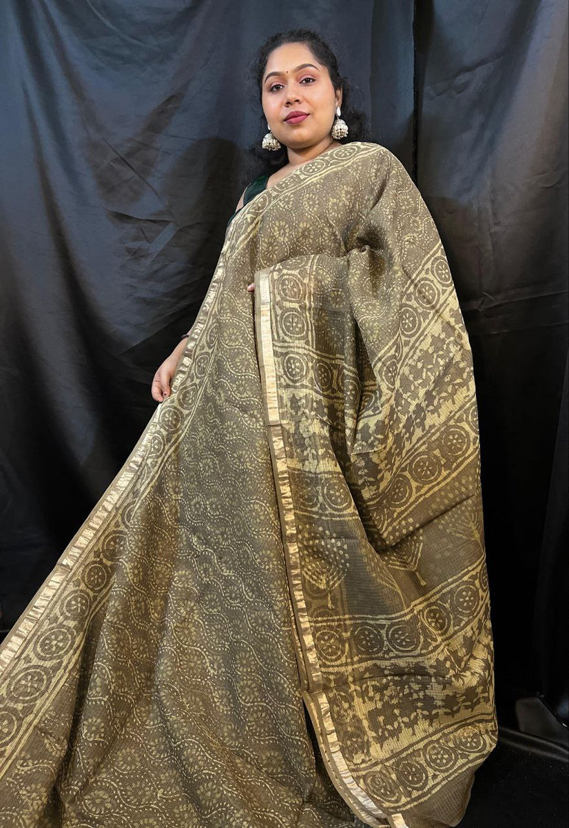 Woman wearing a traditional patterned saree against a black background