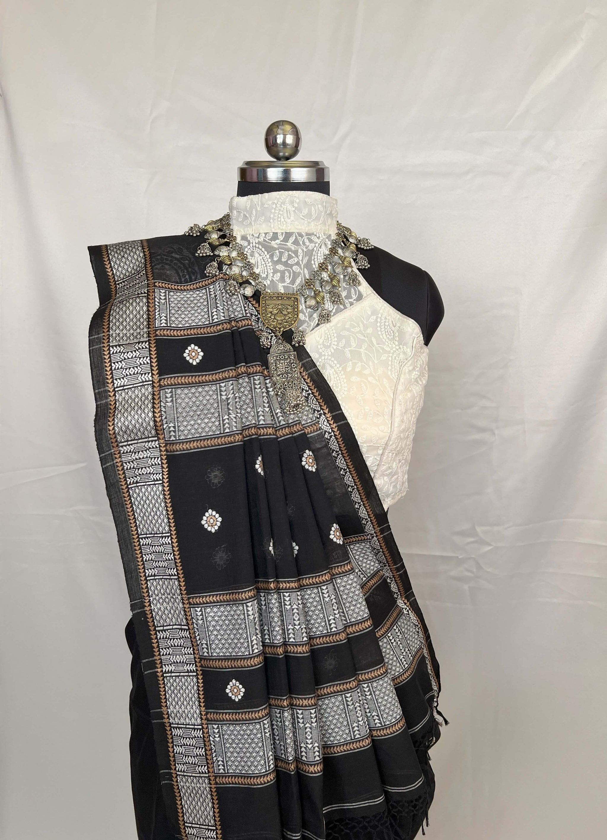 Black and white embroidered saree on a mannequin against a white background