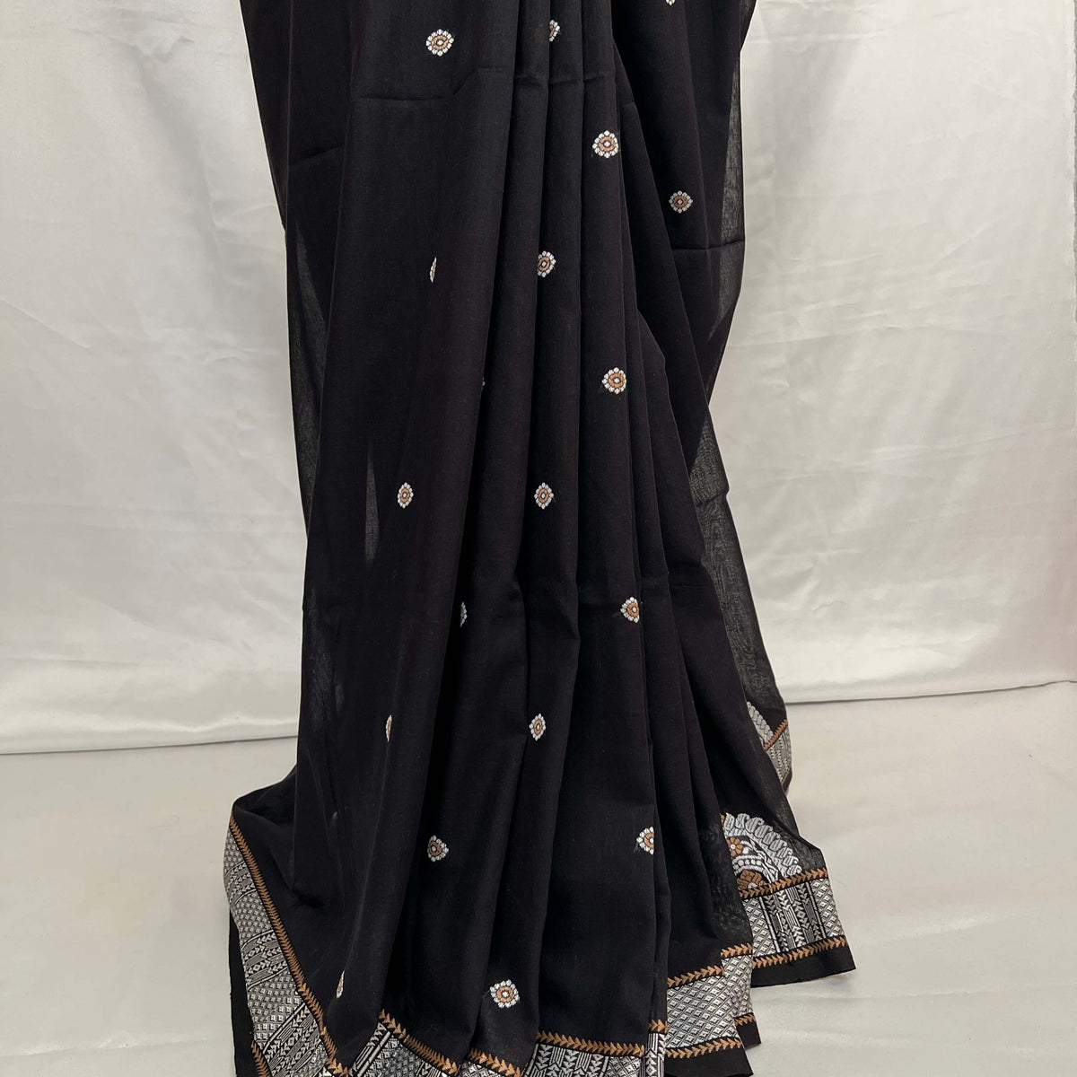Black saree with white and gold embroidery on a white background