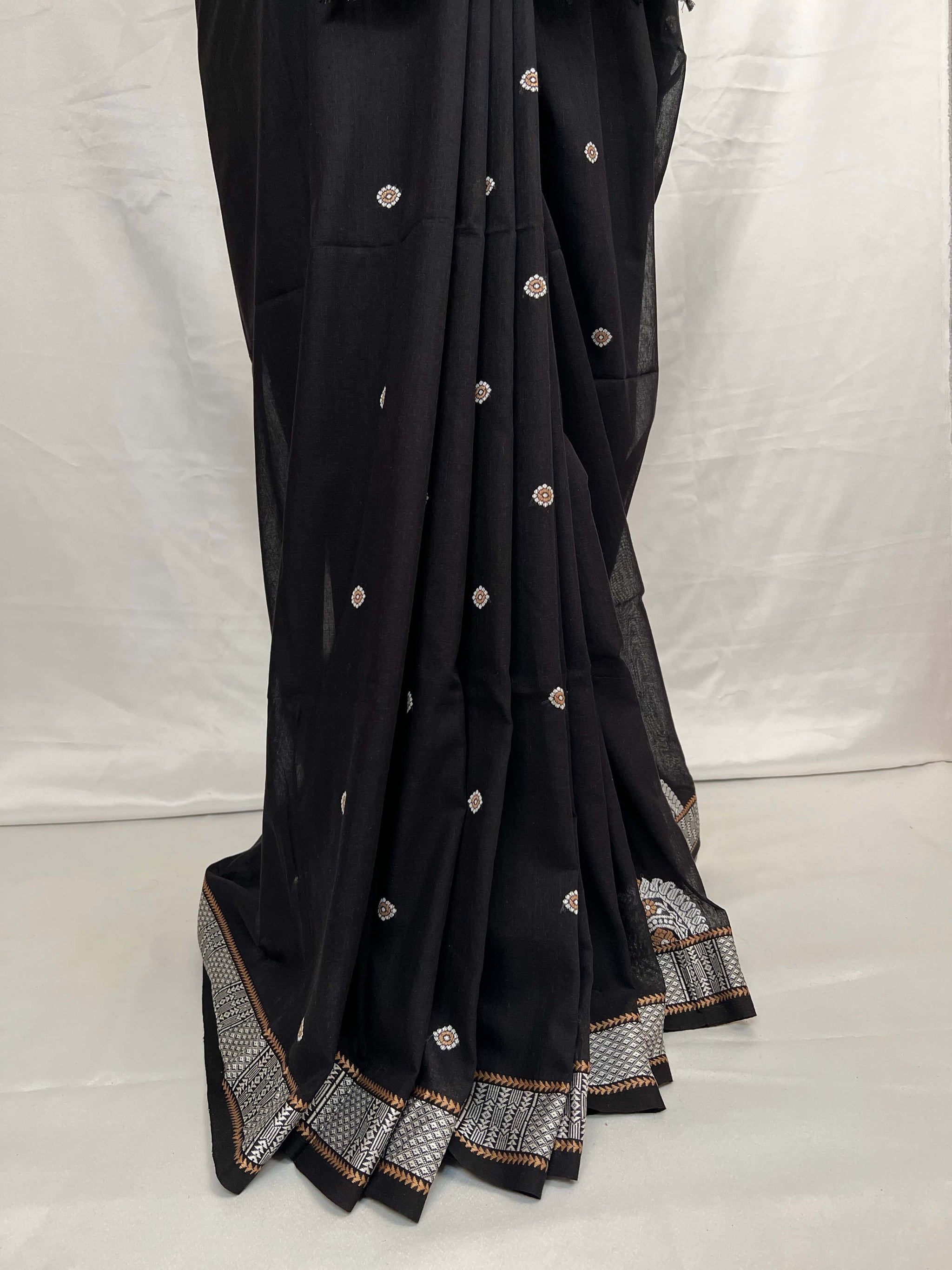Black saree with white and gold embroidery on a white background