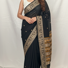 Woman wearing a black saree with gold embroidery on a white background