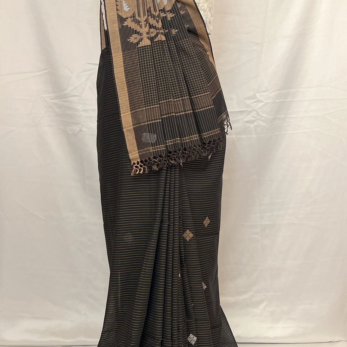 Black saree with gold border on a mannequin against a white background