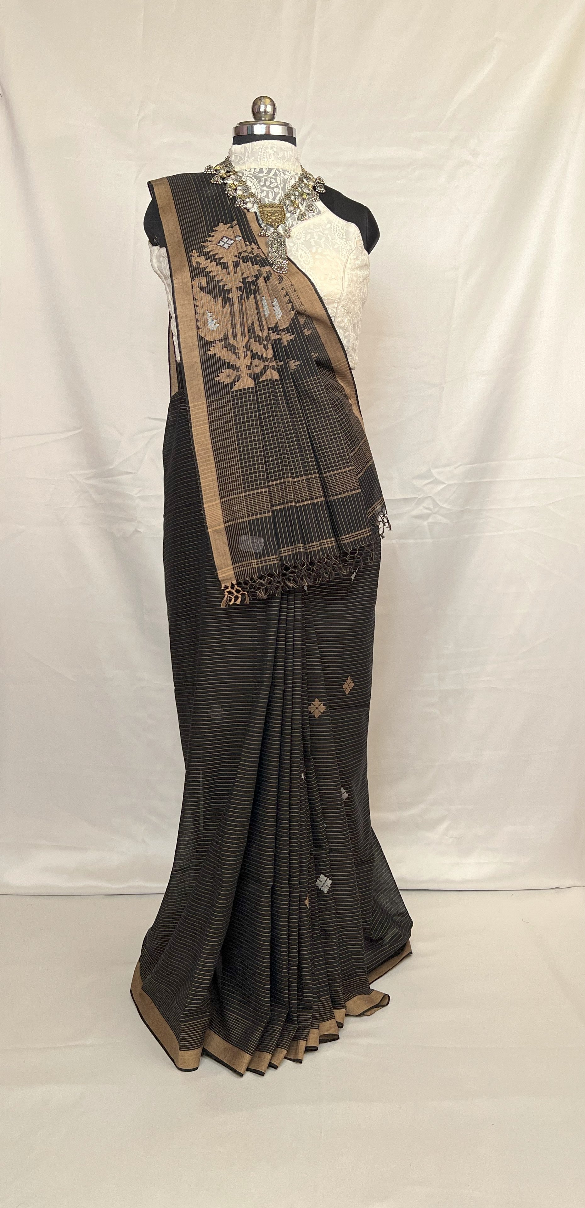 Black saree with gold border on a mannequin against a white background