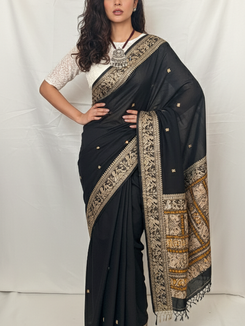Woman wearing a black saree with gold patterns against a white background