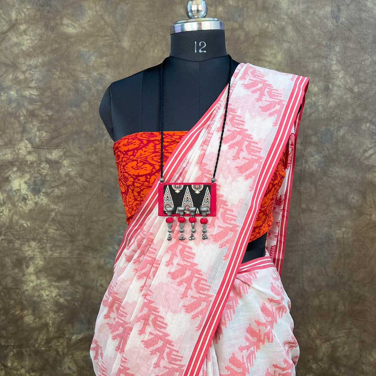 Close-up of intricate weaving details on red white handloom cotton saree.