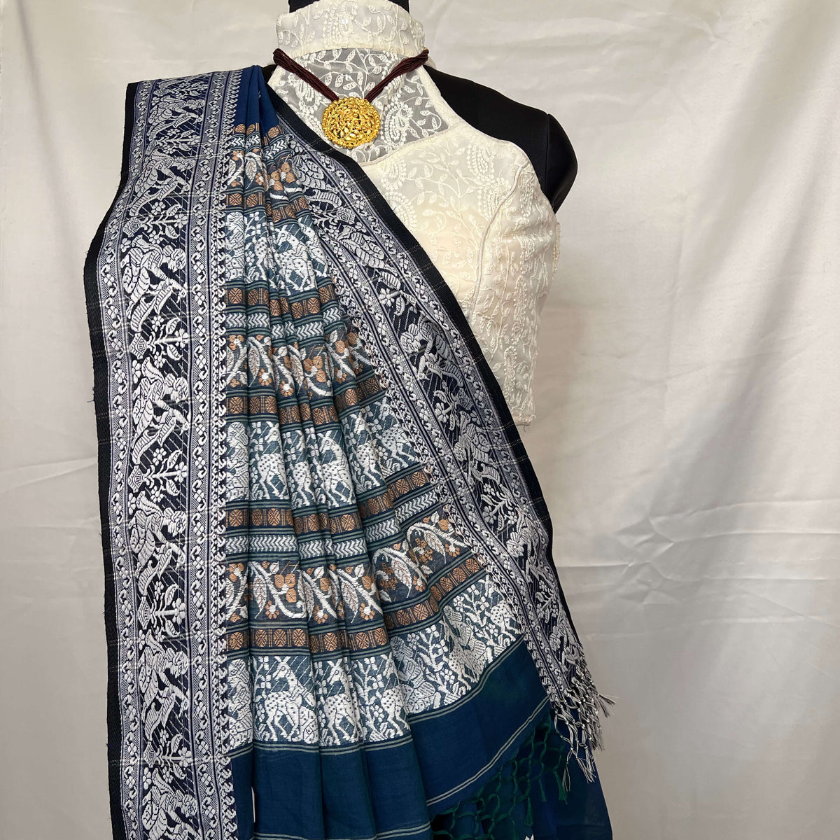 Peacock blue cotton Baluchari saree with heritage woven motifs and delicate handloom craft.