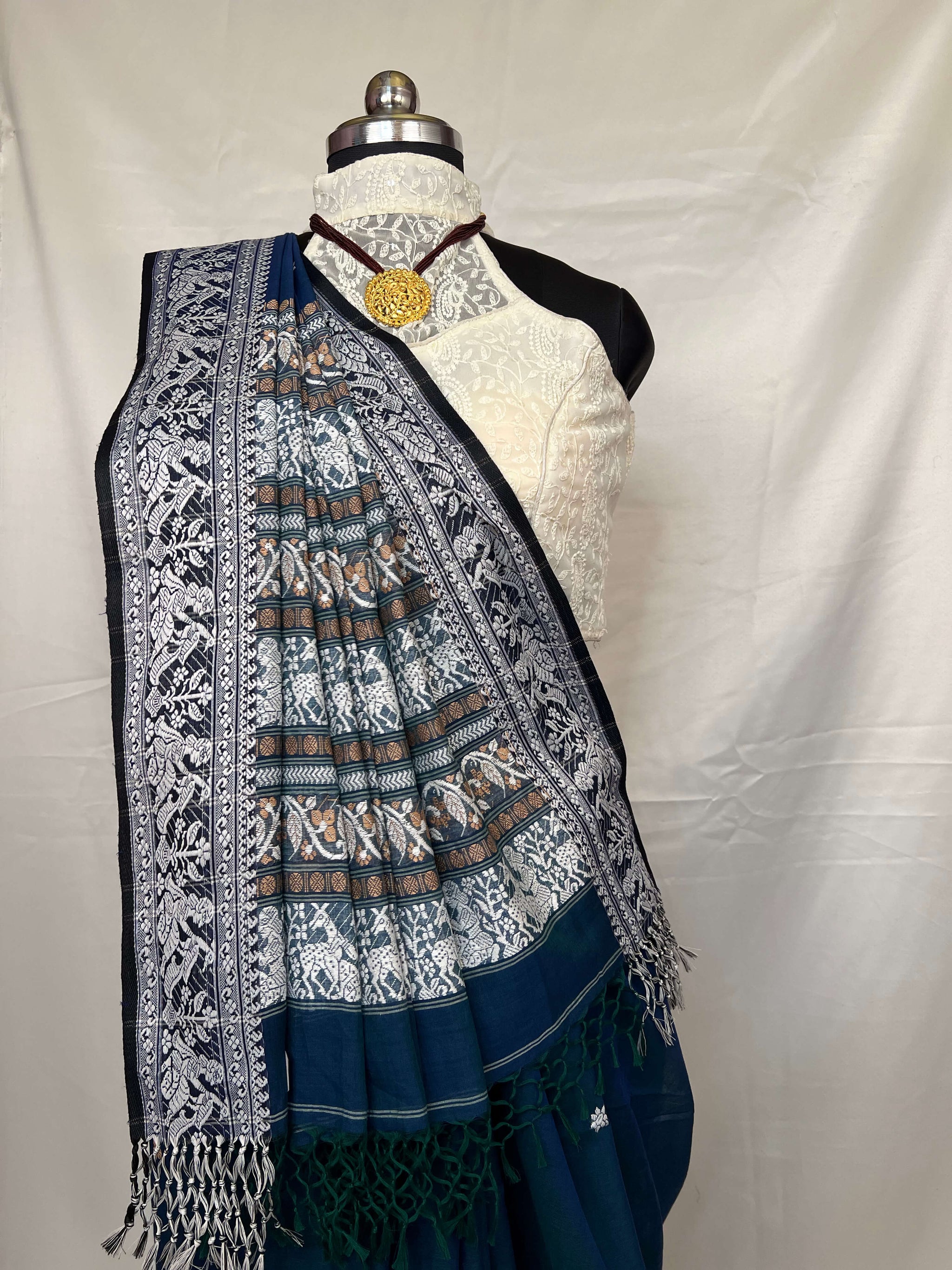 Peacock blue cotton Baluchari saree with heritage woven motifs and delicate handloom craft.