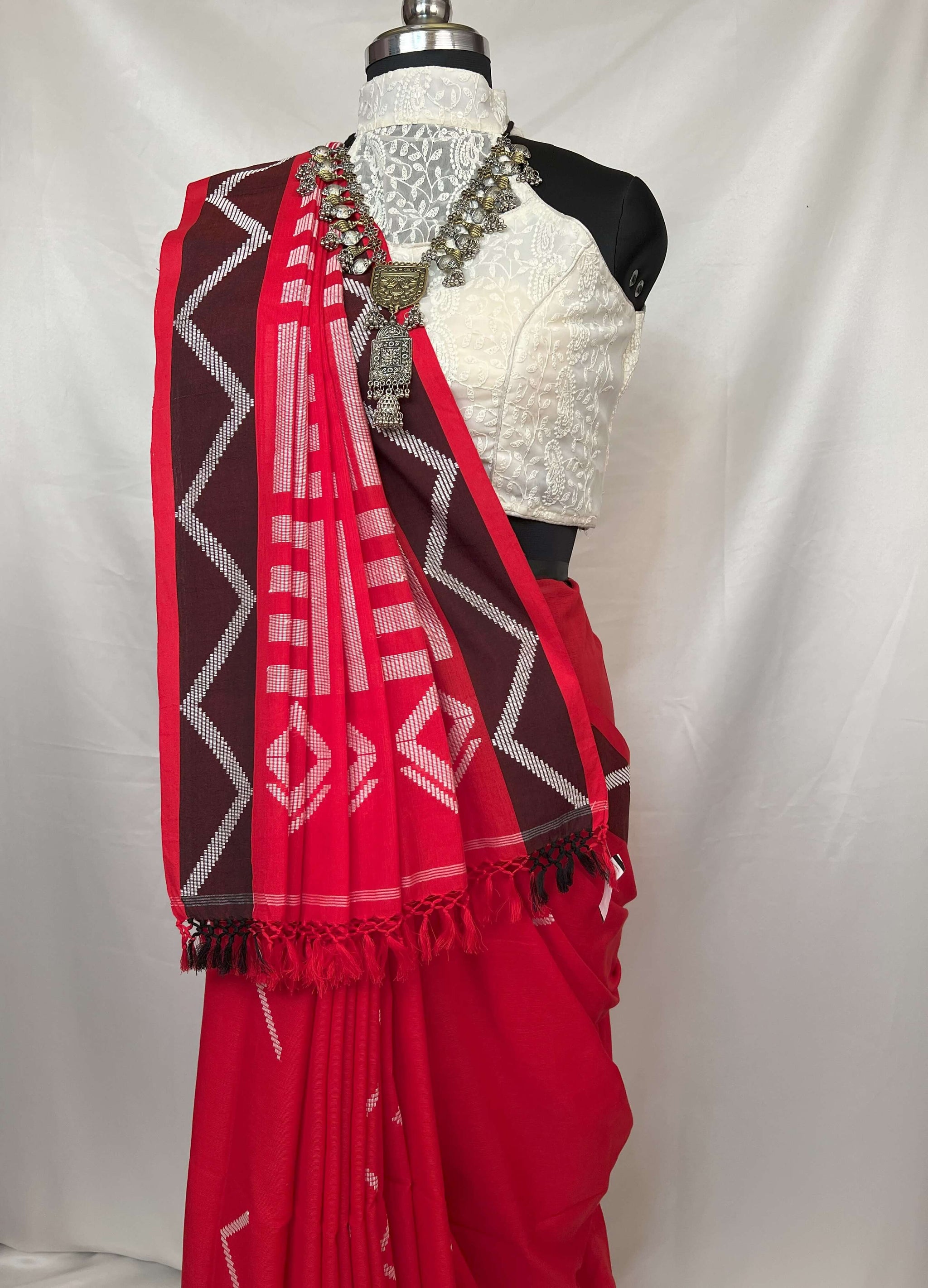 Red and white patterned scarf draped over a mannequin wearing a black and white outfit on a white background