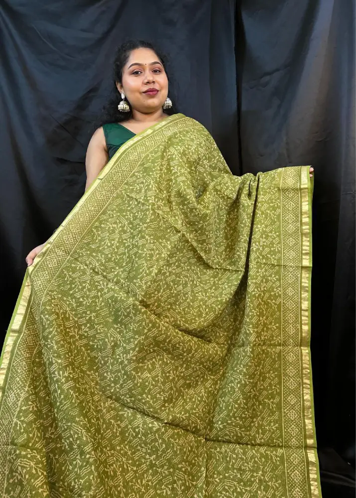 Woman draped in green Kota saree with woven white border
