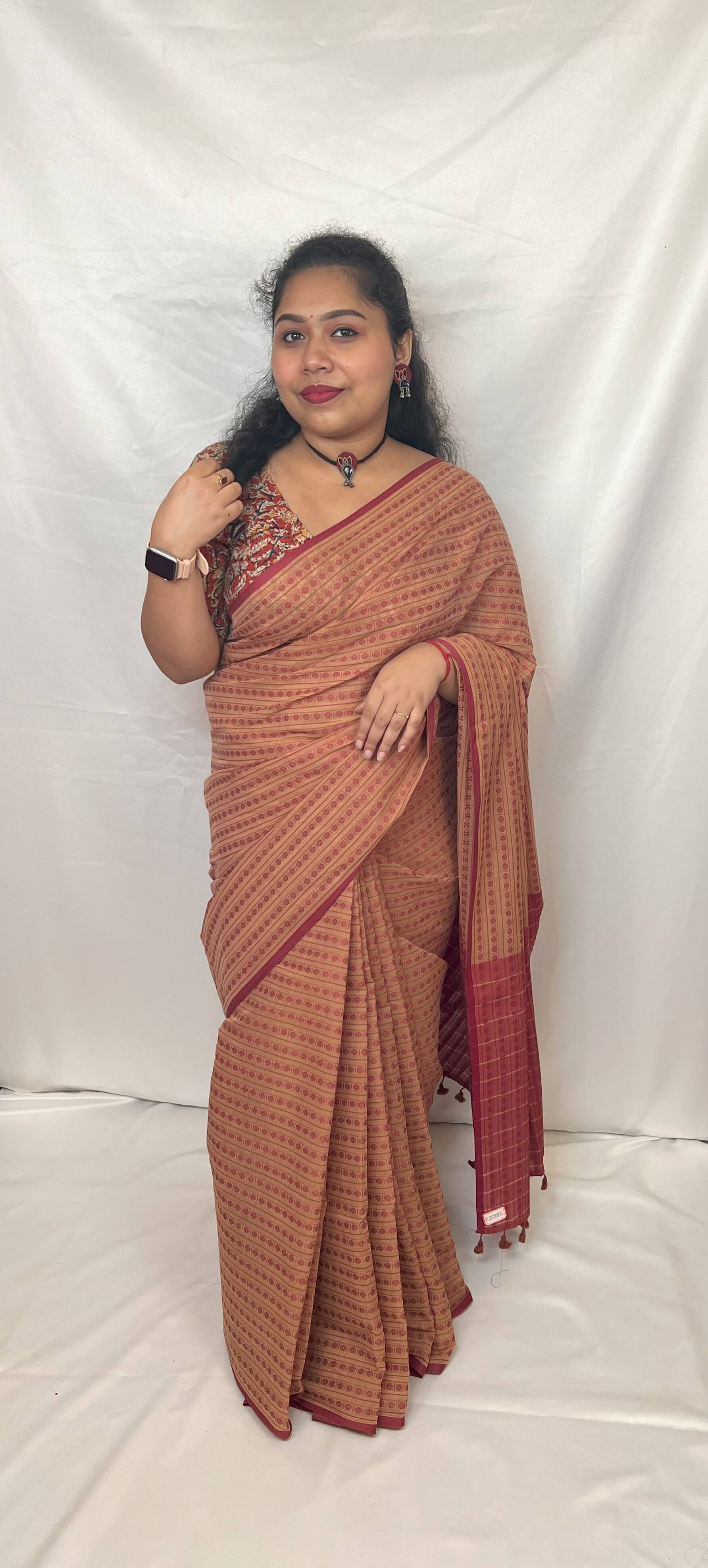 Woman wearing beige cotton handloom saree with red motifs.