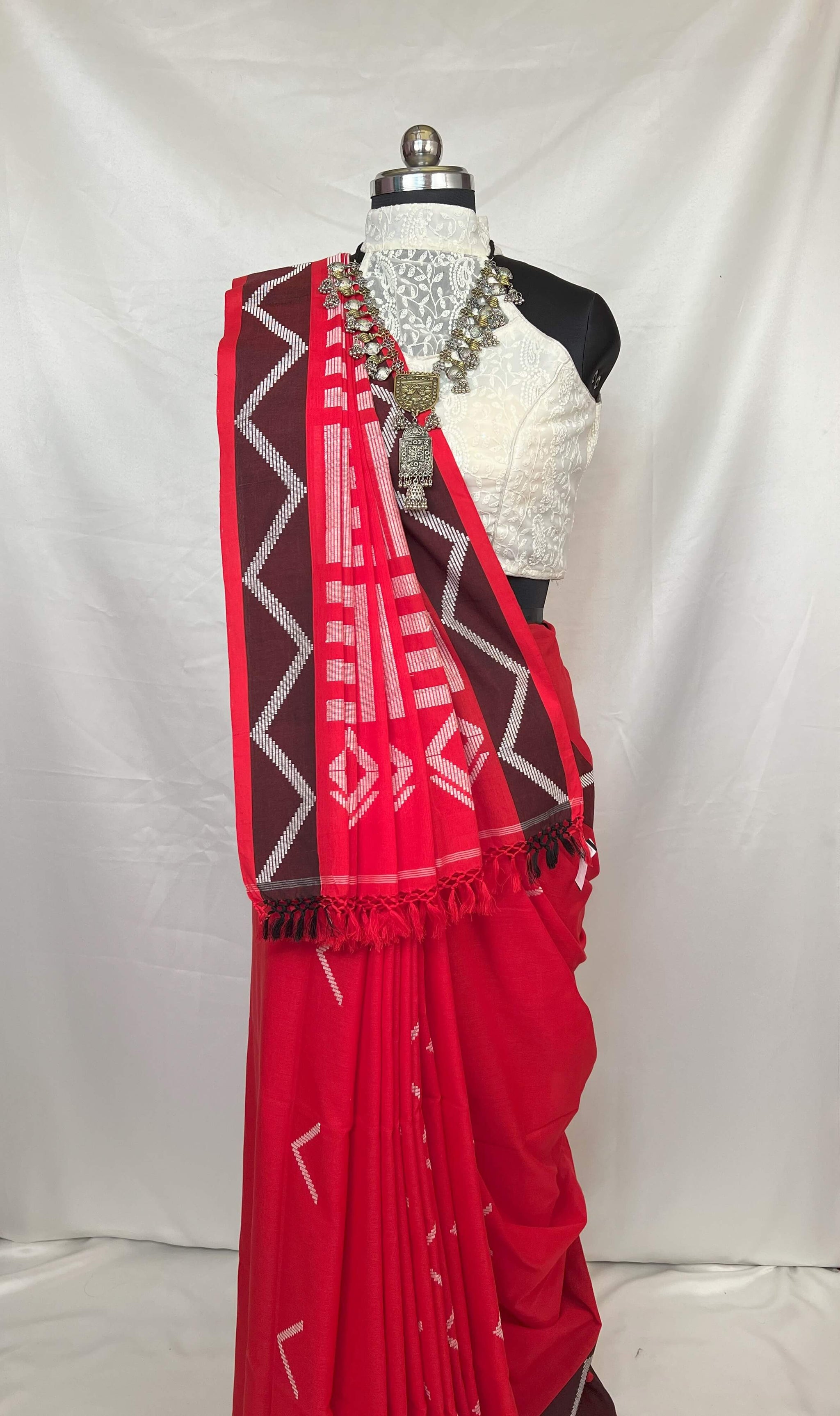 Ethnic red white handloom cotton saree styled with jewelry, perfect for traditional events.