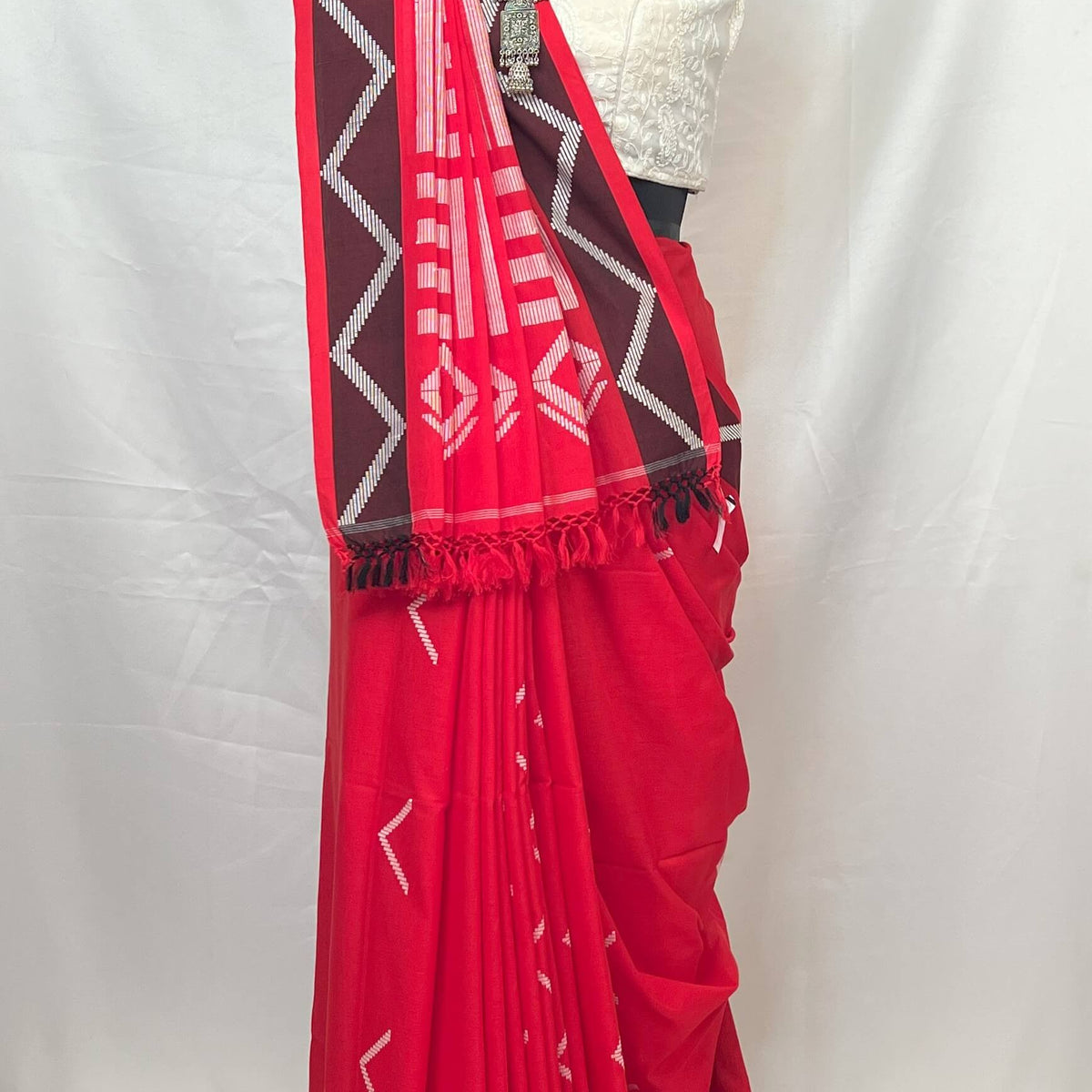 Red saree with Chocolate and white patterns on a mannequin against a white background