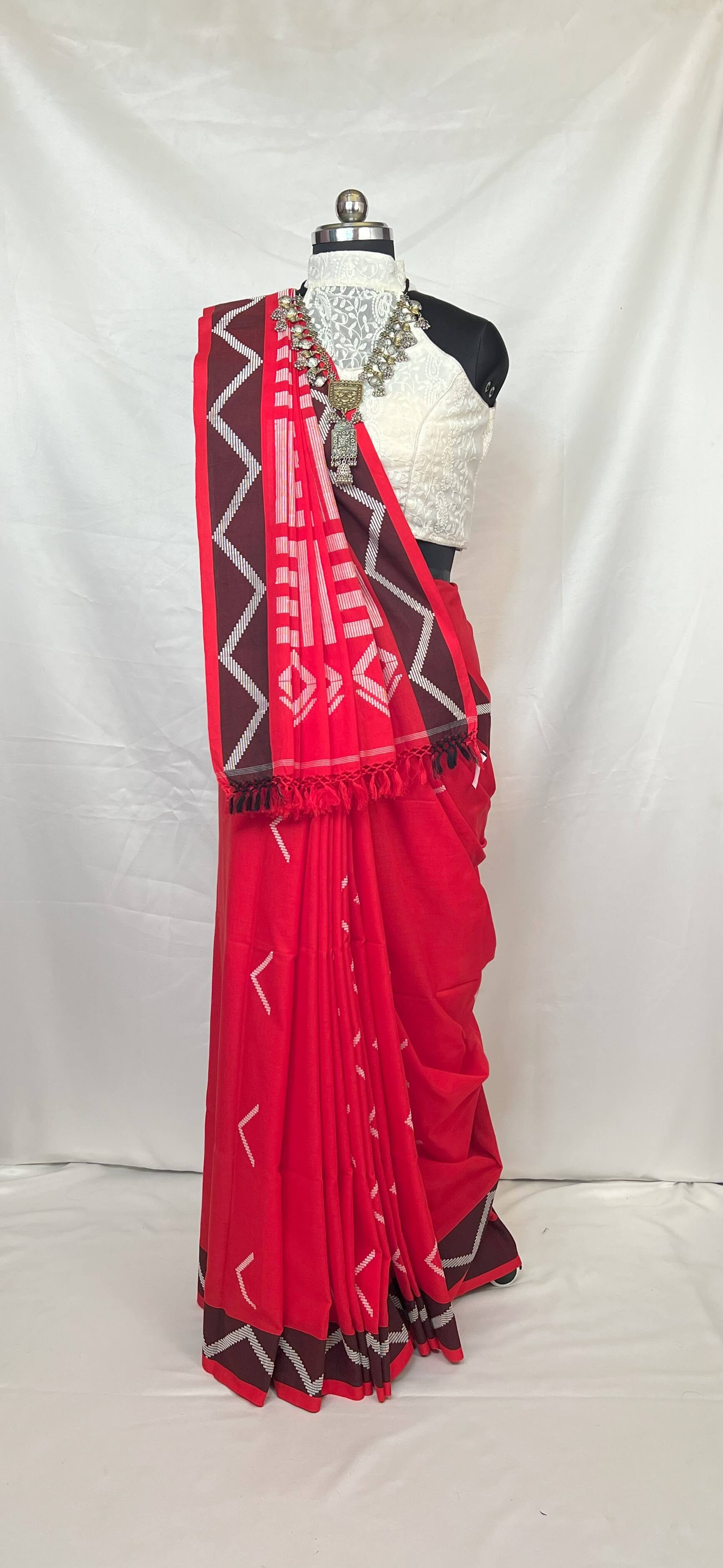 Red saree with Chocolate and white patterns on a mannequin against a white background