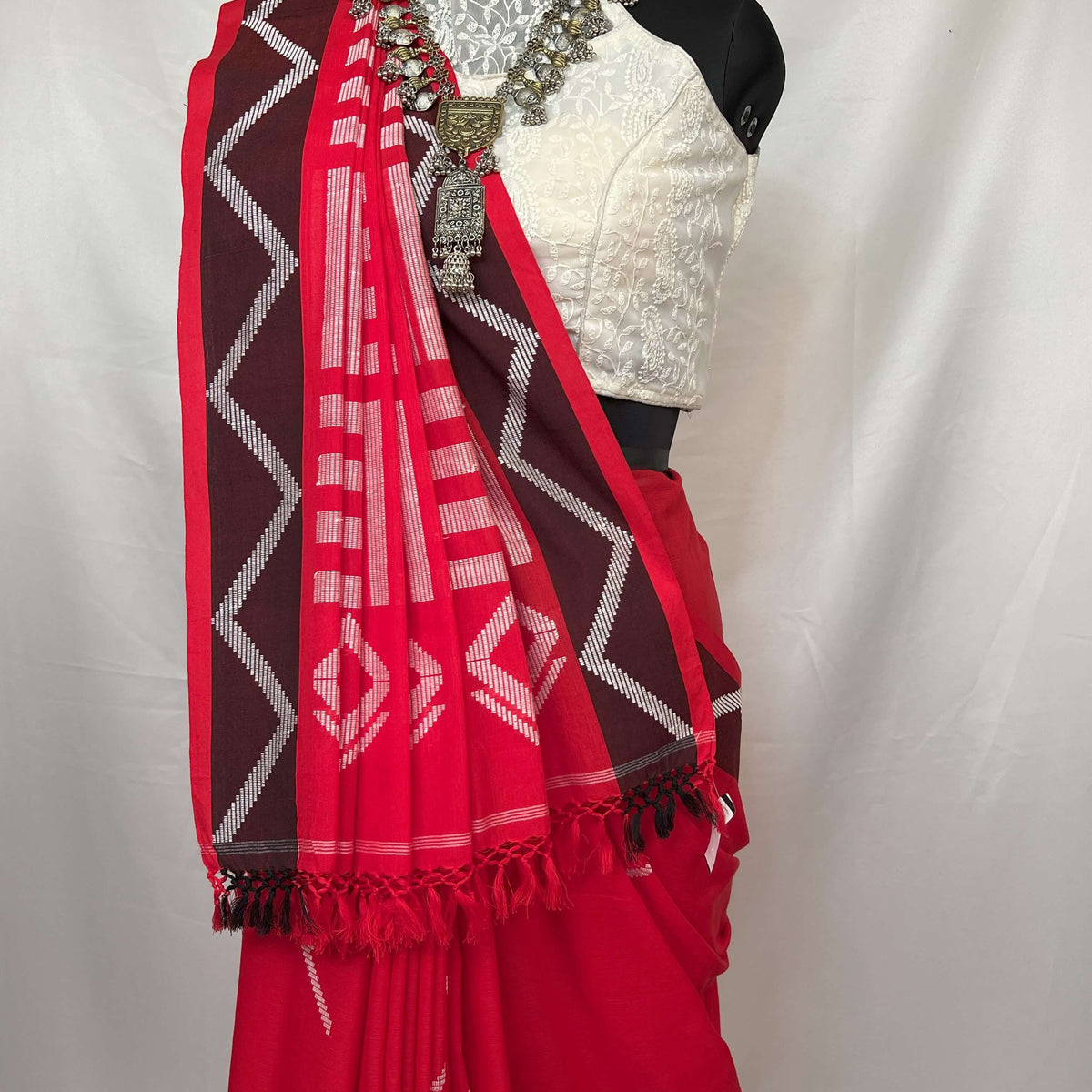 Elegant saree in red and white handloom cotton with geometric borders and soft cotton texture.